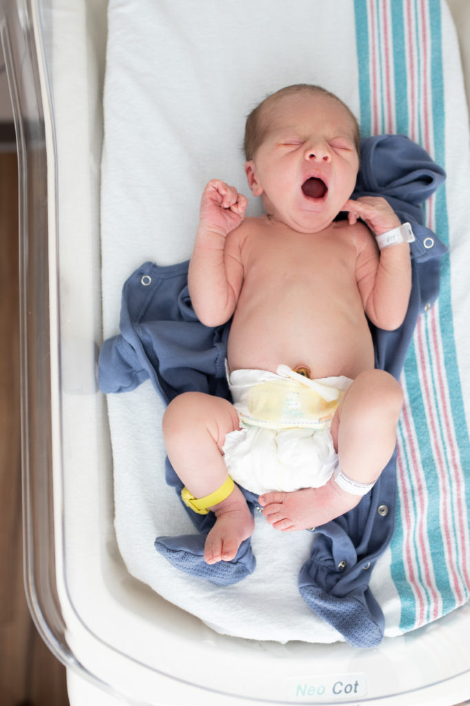 newborn baby yawns in bassinet