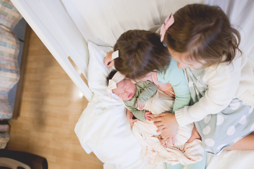siblings holding newborn in hospital