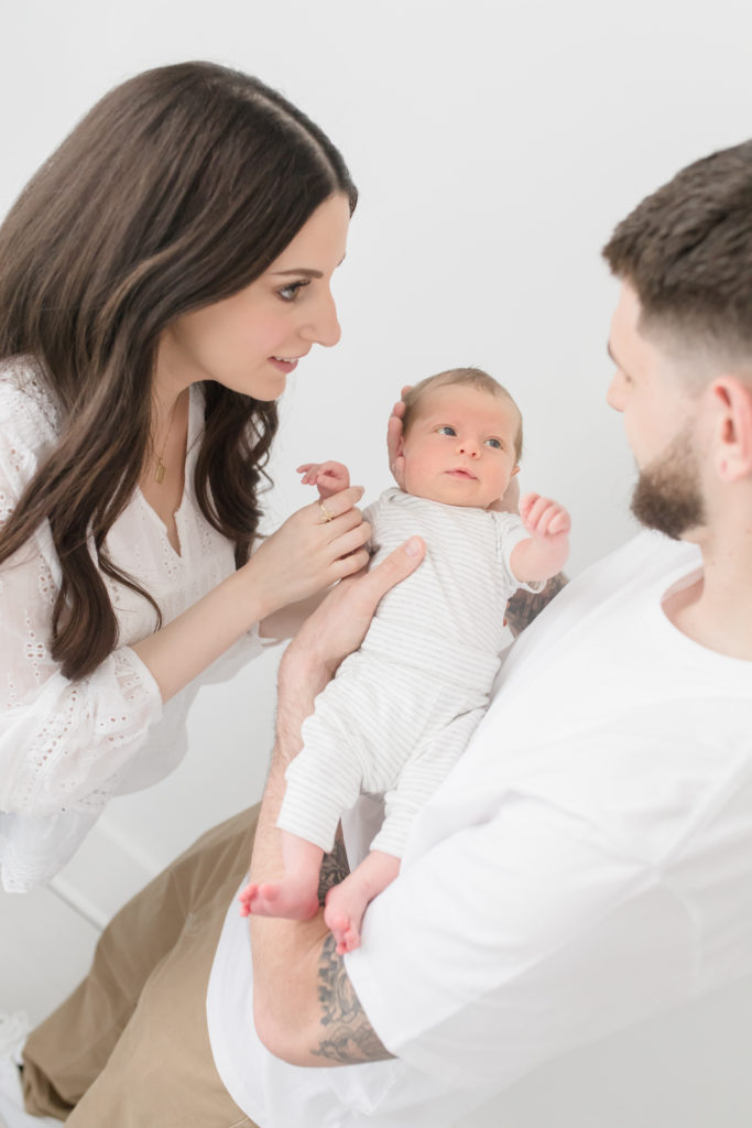 Newborn baby looking up at dad during photoshoot